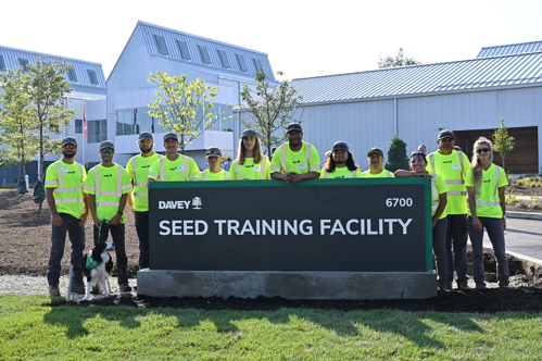A group of Davey employees gathered around the SEED Training Facility welcome sign.