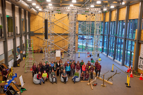 A group is photographed in front of the climbing structure inside the SEED Campus building.